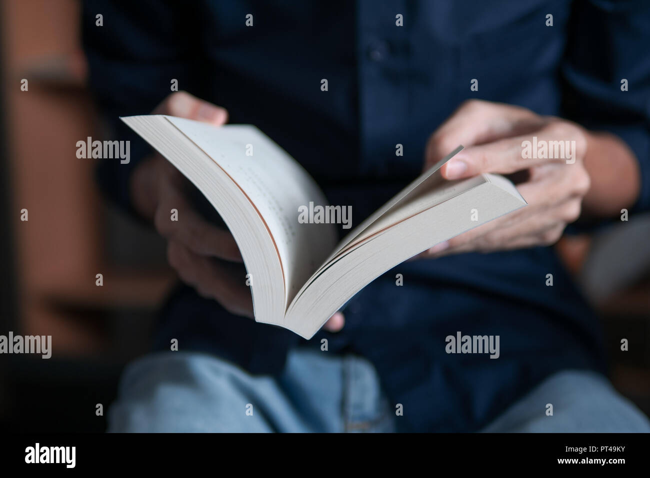 Man in blue shirt reading a book Stock Photo