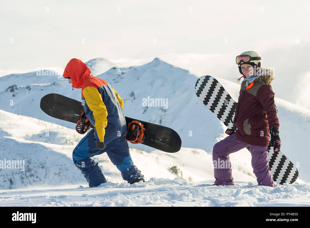 Couple snowboarding freeriders man and a woman go with snowboards on the ridge. Stock Photo