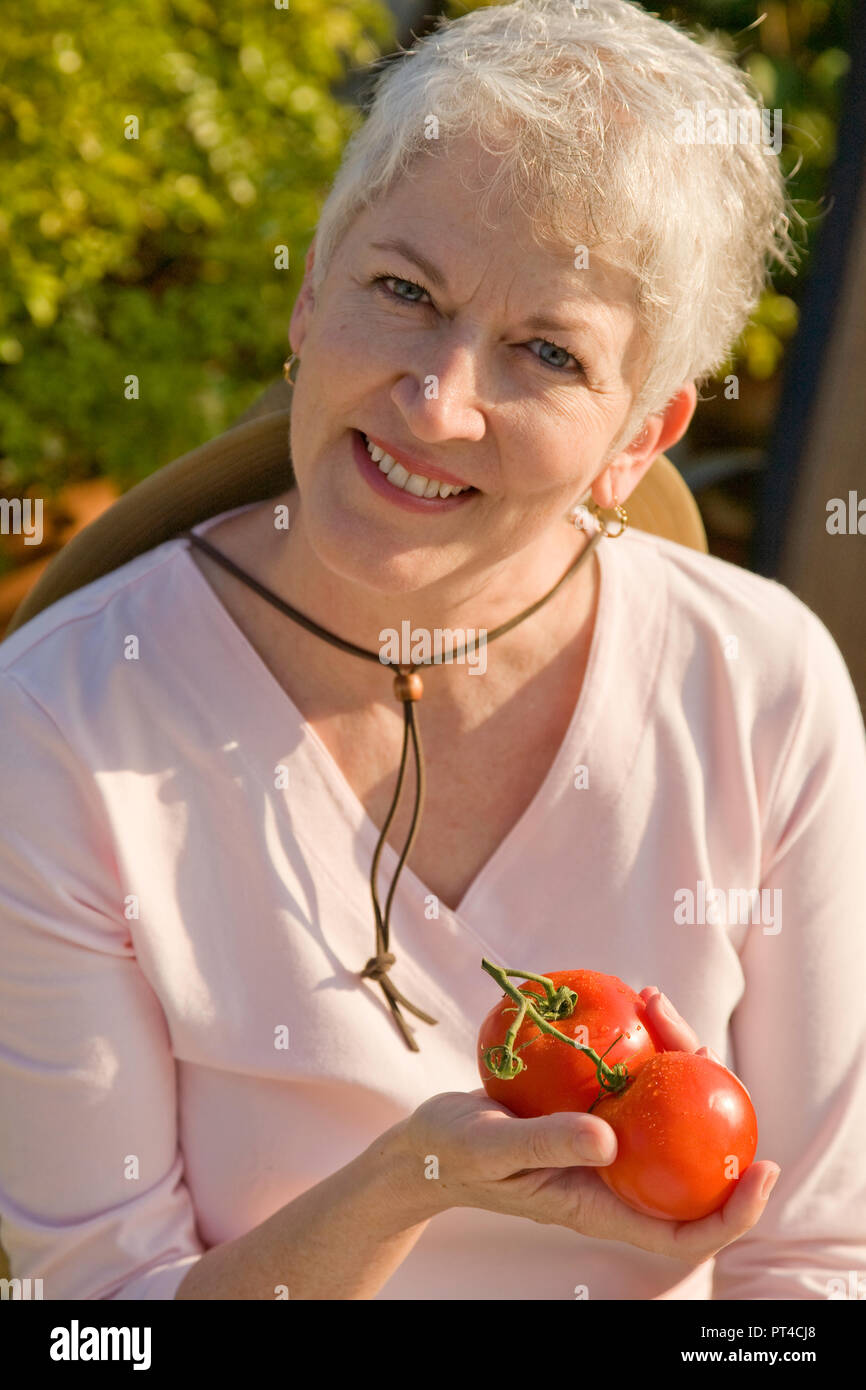 Senior woman shows off ripe tomatoes in her garden, USA Stock Photo - Alamy