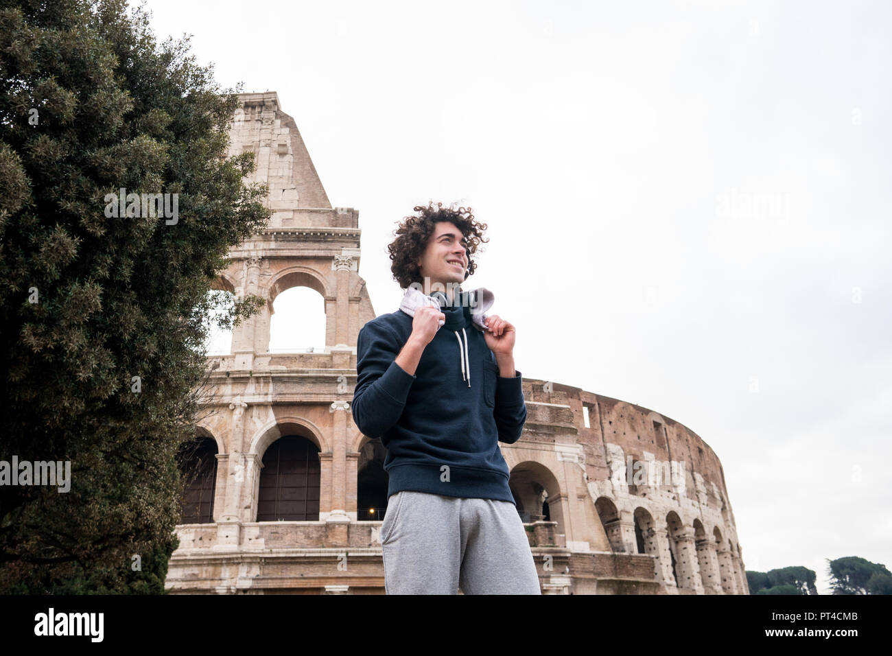 Handsome young sportsman relaxing after training with a towel around his neck in front of Colosseum in Rome Stock Photo