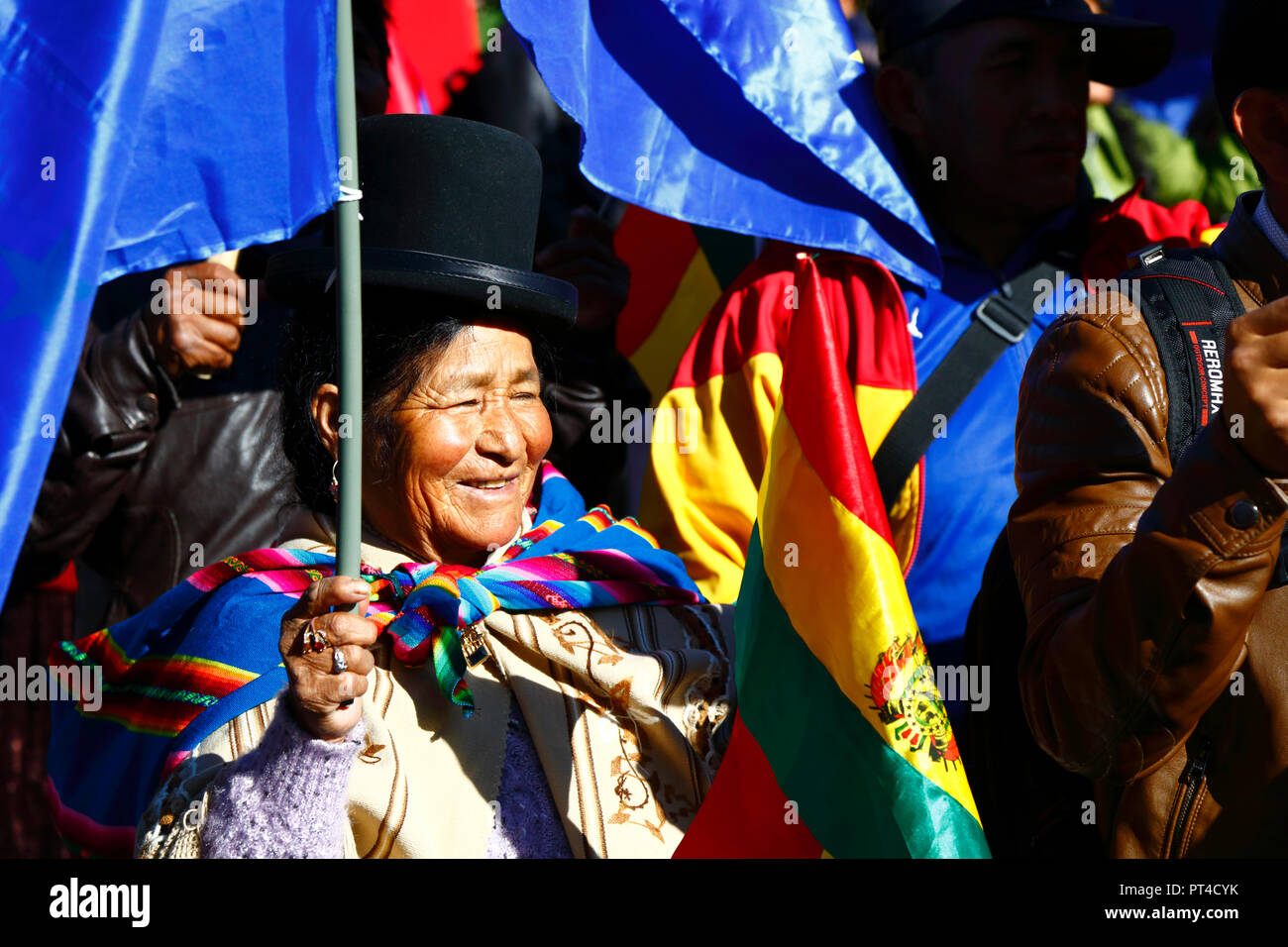 An Aymara woman or cholita and the Bolivian national flag at an event, La Paz, Bolivia. Stock Photo