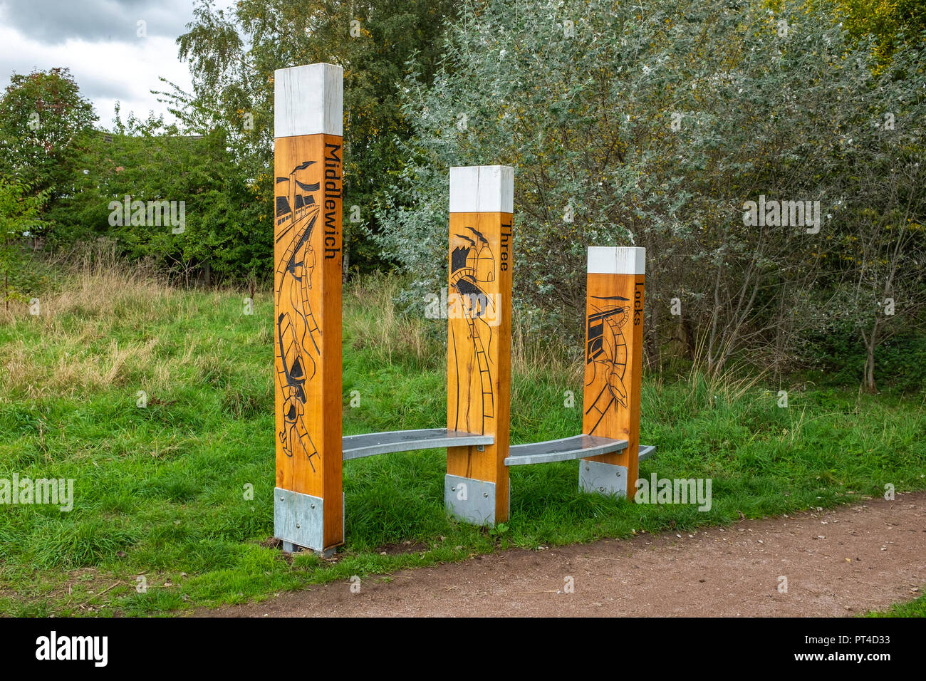 Canal Way Marker and oak benches on the Trent and Mersey Canal in Middlewich Cheshire UK Stock Photo