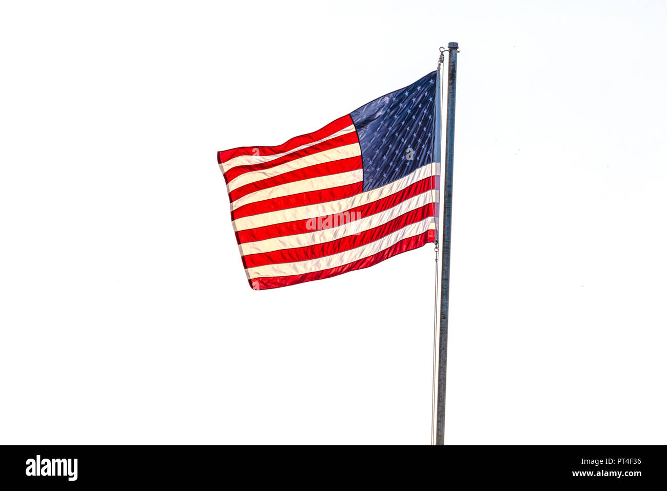 United States flag flying on a flag pole aganist a white background Stock Photo