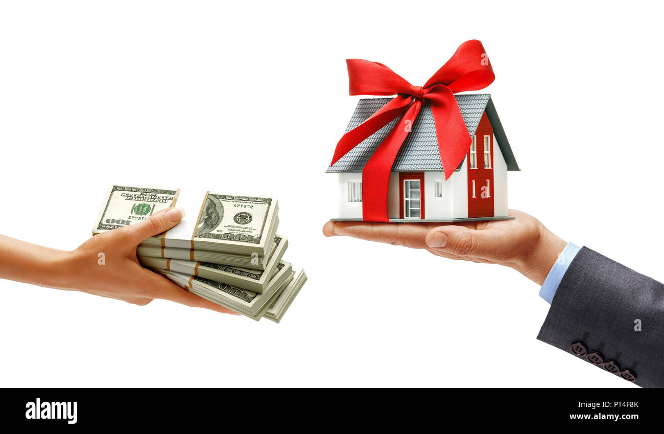 Woman's hand giving bundles of money and man's hand in suit holding house with red ribbon isolated on white background. Close up. High resolution prod Stock Photo