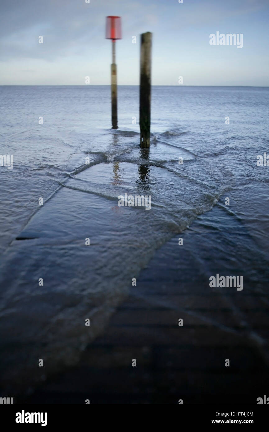 Tide rising over wooden jetty with navigation can marker, Central Promenade, Cleethorpes, UK. Stock Photo