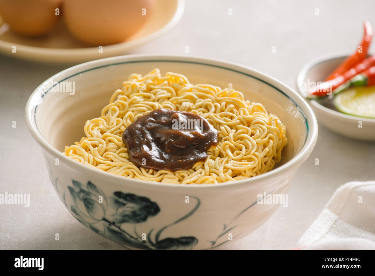 Instant noodles in bowl and vegetable side dishes on stone background. Quick & easy food concept. Stock Photo