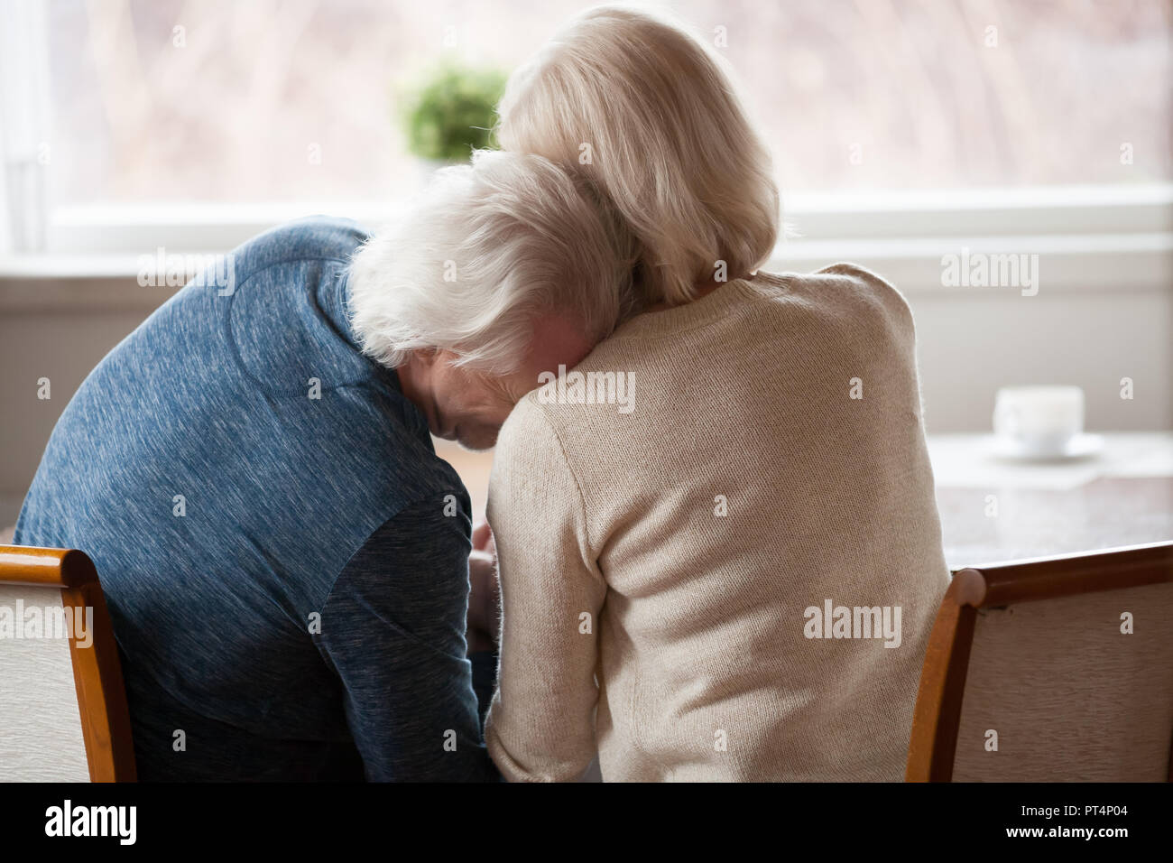 Rear back view at senior retired grey haired man leaning on shoulder of mature loving woman crying or laughing, older middle aged couple bonding, trus Stock Photo