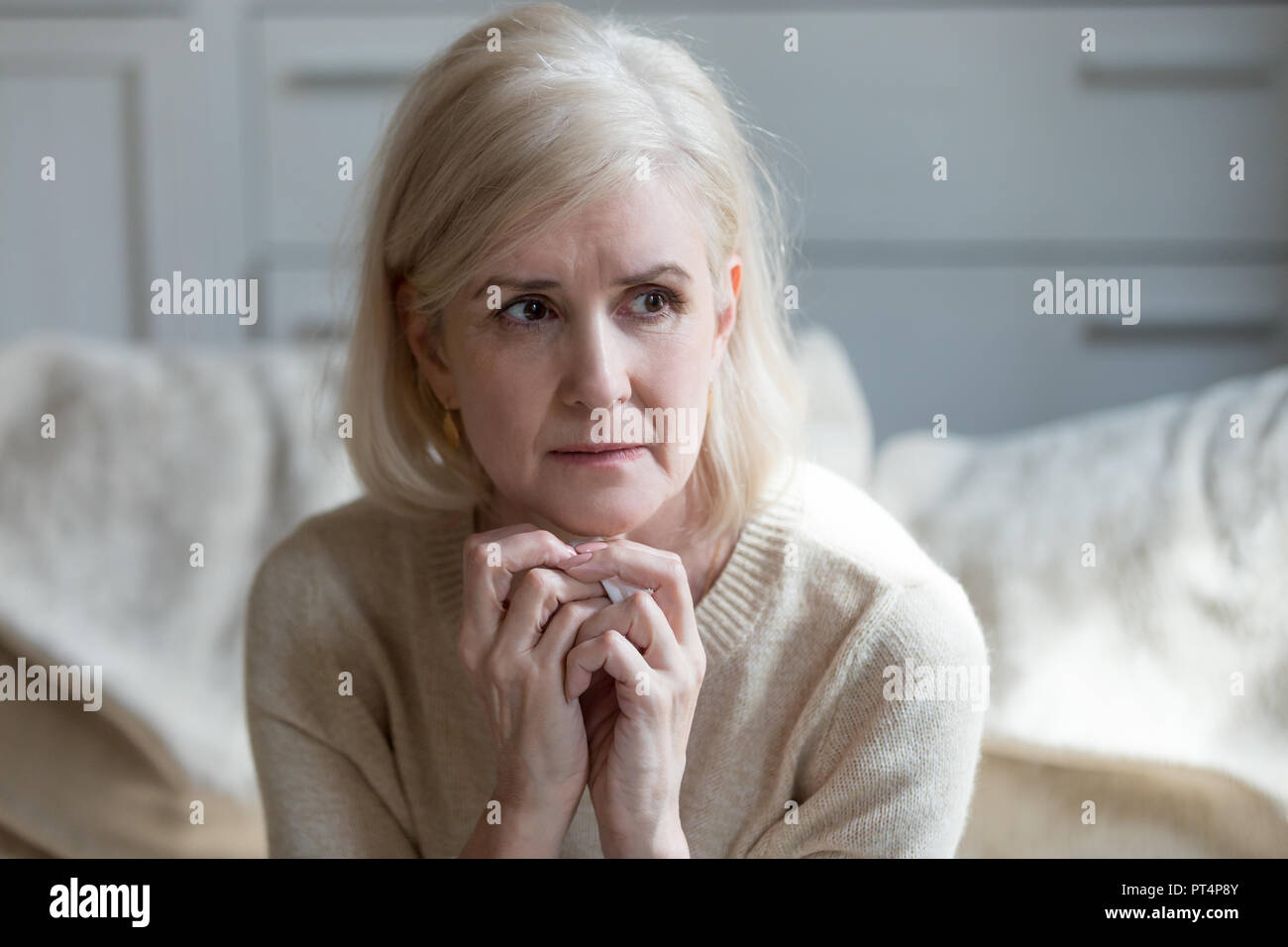 Thoughtful upset mature lady crying thinking of loneliness or gr Stock Photo