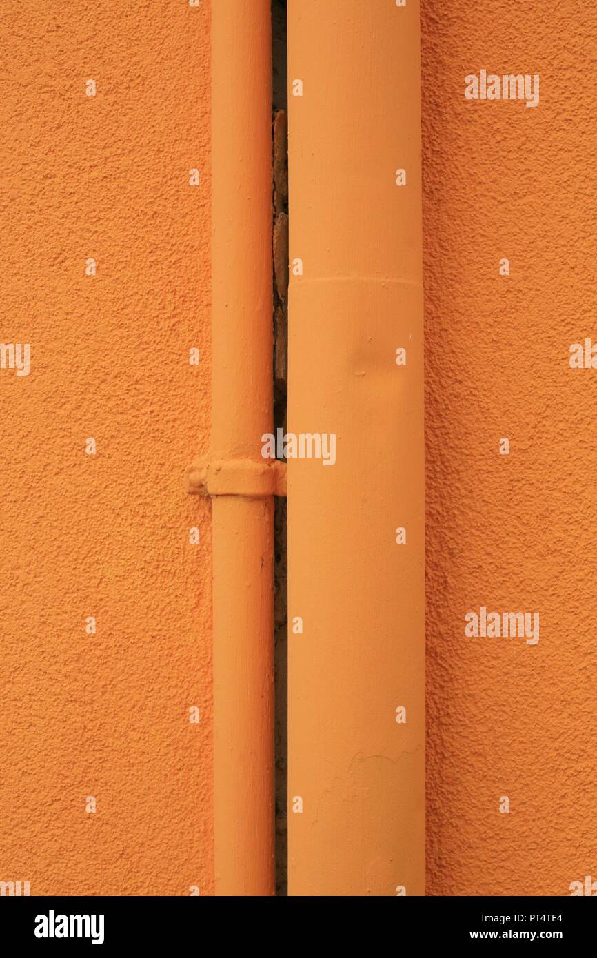 Orange pipes up an orange wall Stock Photo