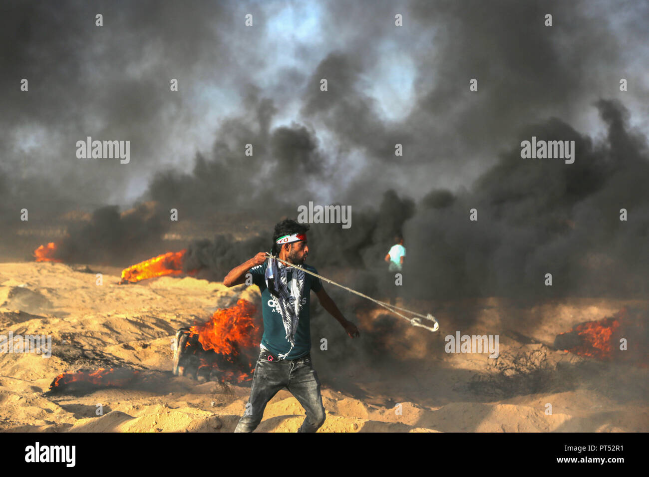 October 1, 2018 - Khan Yunis, Gaza, Palestine - A palestinian demonstrator seen throwing stones at Israeli troops east of Khuza'a in southern Gaza..Hundreds of palestinian demonstrators burn tyres and throw rocks using slingshots in response to Israeli forces' intervention during a demonstration within the 'Great March of Return' on the Gaza-Israel border. (Credit Image: © Yousef Masoud/SOPA Images via ZUMA Wire) Stock Photo