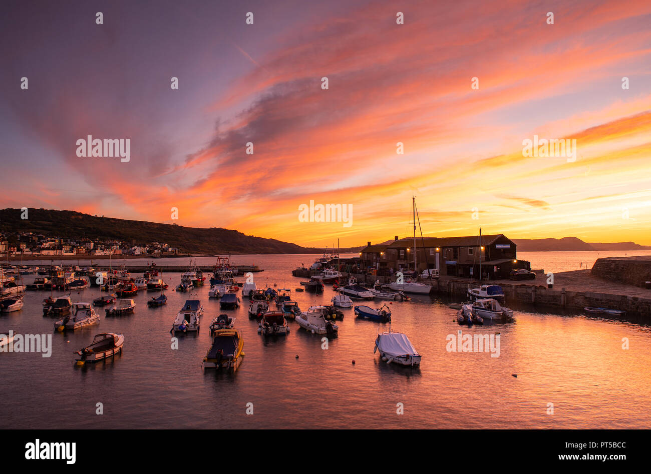 Lyme Regis, Dorset, UK. 7th October 2018.  UK Weather:  The skies over the Cobb Harbour glow with vibrant colour at the start of a bright and sunny autumn day at Lyme Regis.  Credit: Celia McMahon/Alamy Live News Stock Photo