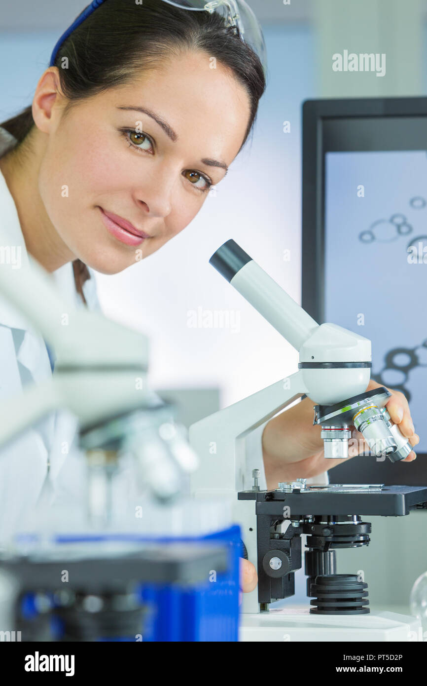 Doctor, female medical or scientific researcher using her microscope in ...