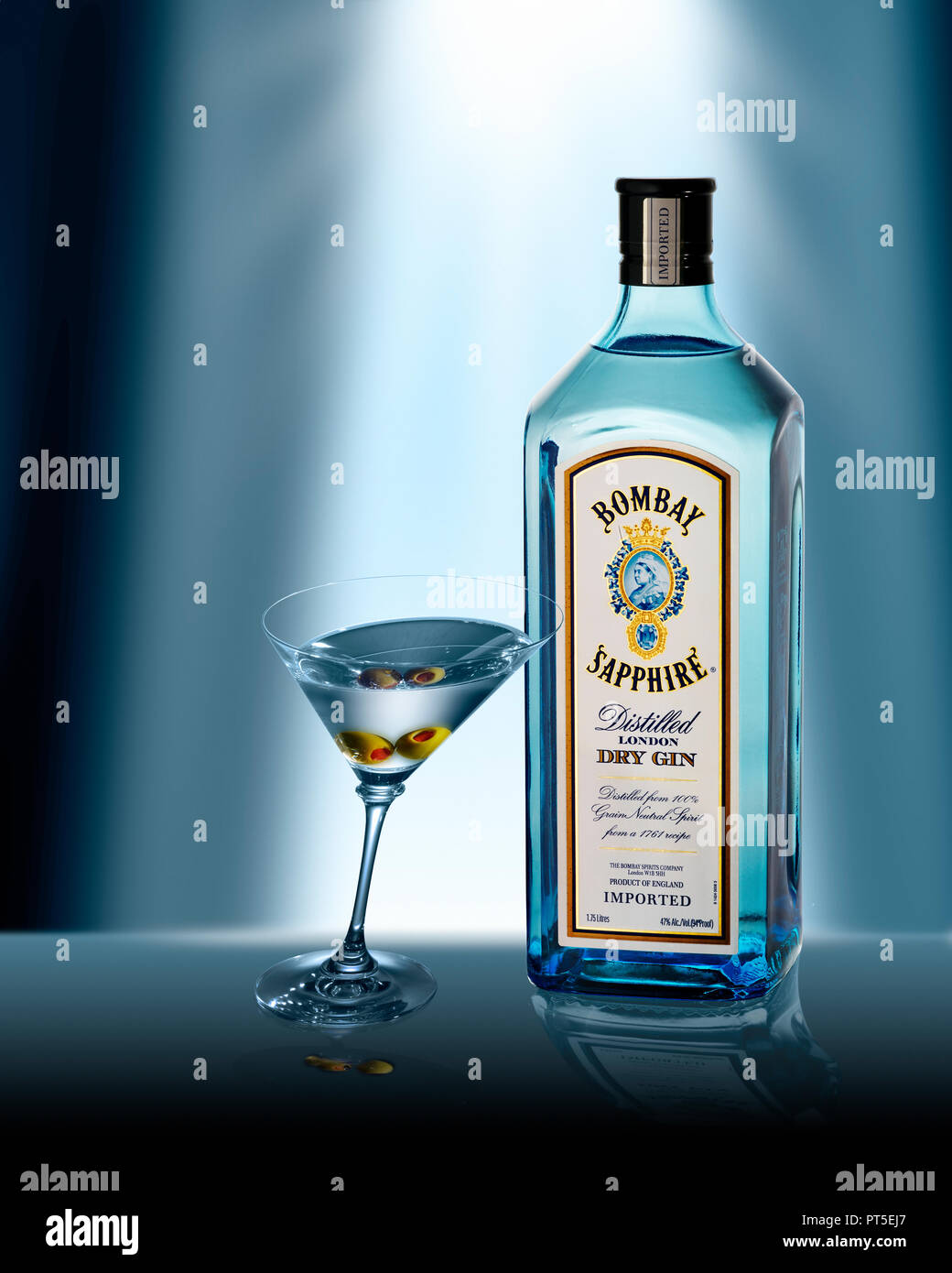 A Martini Glass with 2 two olives leaning on a Bottle of Bombay Sapphire Dry Gin Stock Photo