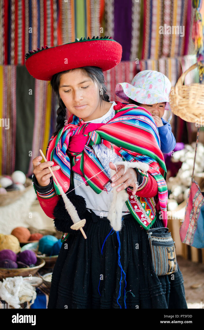 Chinchero, Peru - Sep 15, 2016: A young woman in traditional clothing explains the knitting process which includes the dyeing of alpaca and sheep wool Stock Photo