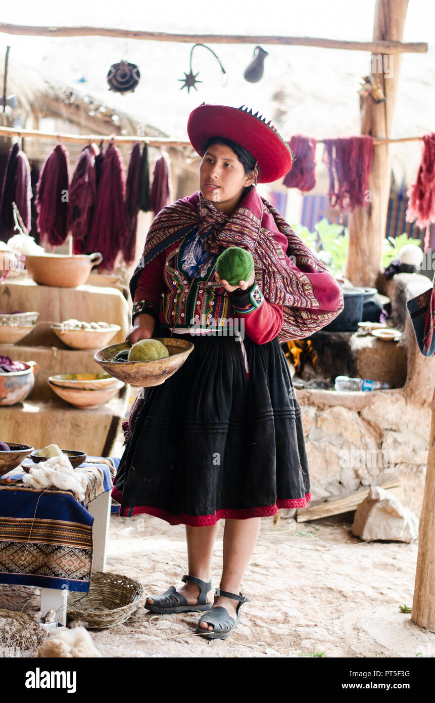 Chinchero, Peru - Sep 15, 2016: A young woman in traditional clothing explains the knitting process which includes the dyeing of alpaca and sheep wool Stock Photo