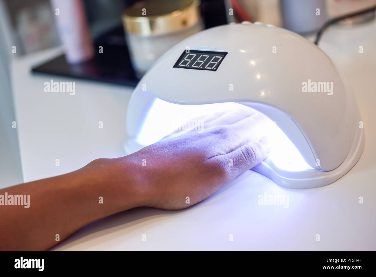 Manicured nails in UV lamp. Small nail art and manicure business. Hands of woman in a wellnes salon Stock Photo