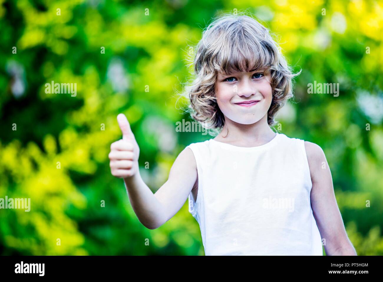 Portrait of young boy showing thumbs up, smiling. Stock Photo
