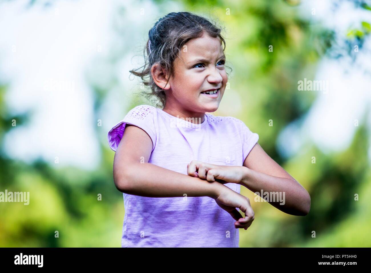 Girl scratching her hand in park. Stock Photo