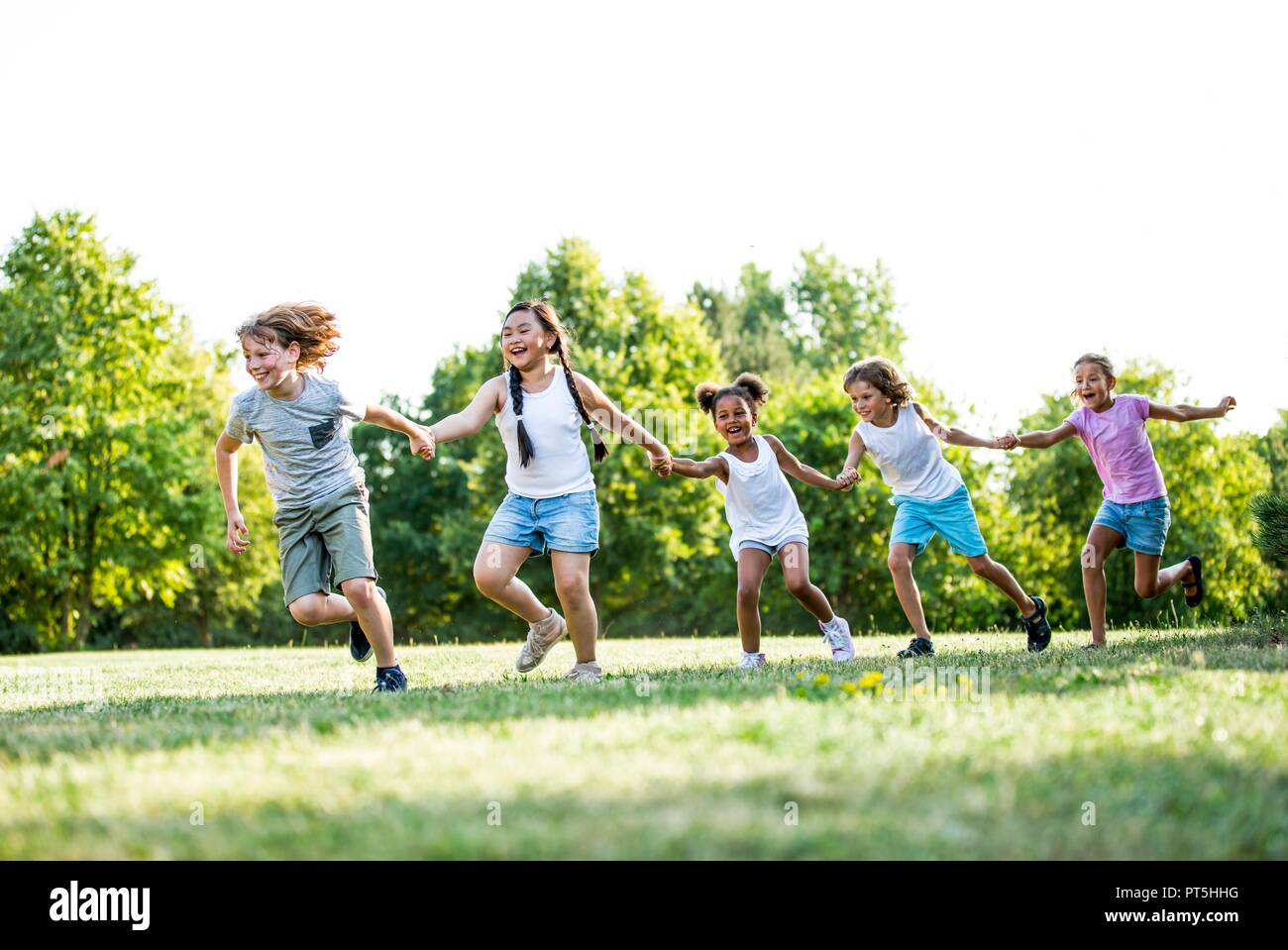 Children holding hands and running in park, laughing Stock Photo - Alamy