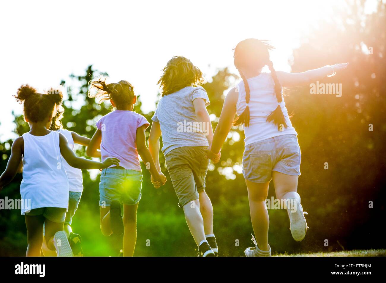 Children holding hands and running in park. Stock Photo