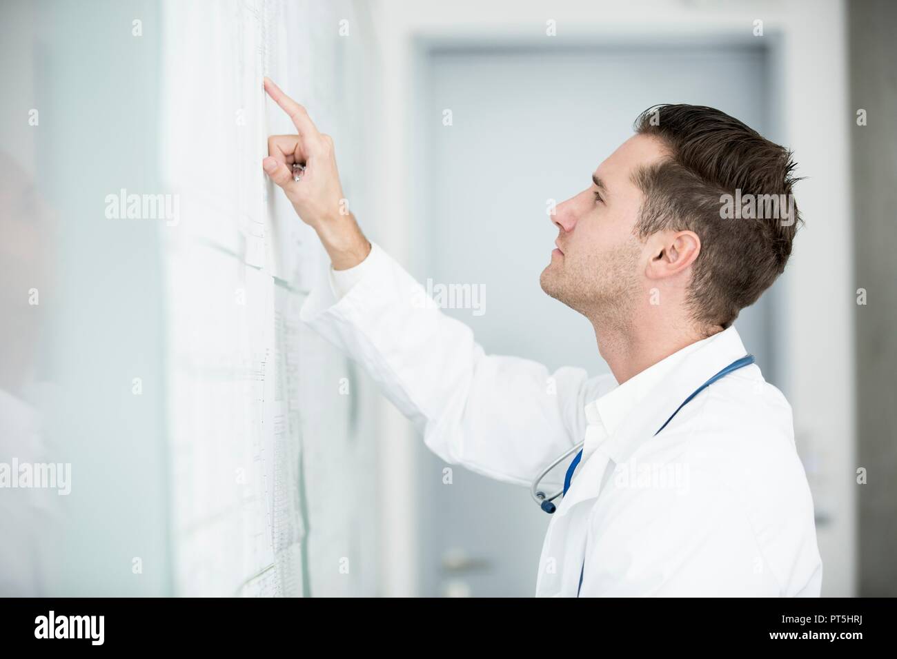 Portrait of mature male doctor inspecting white board. Stock Photo