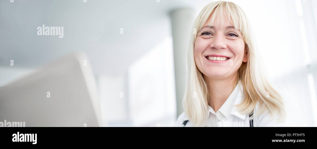 Female doctor using computer and smiling. Stock Photo