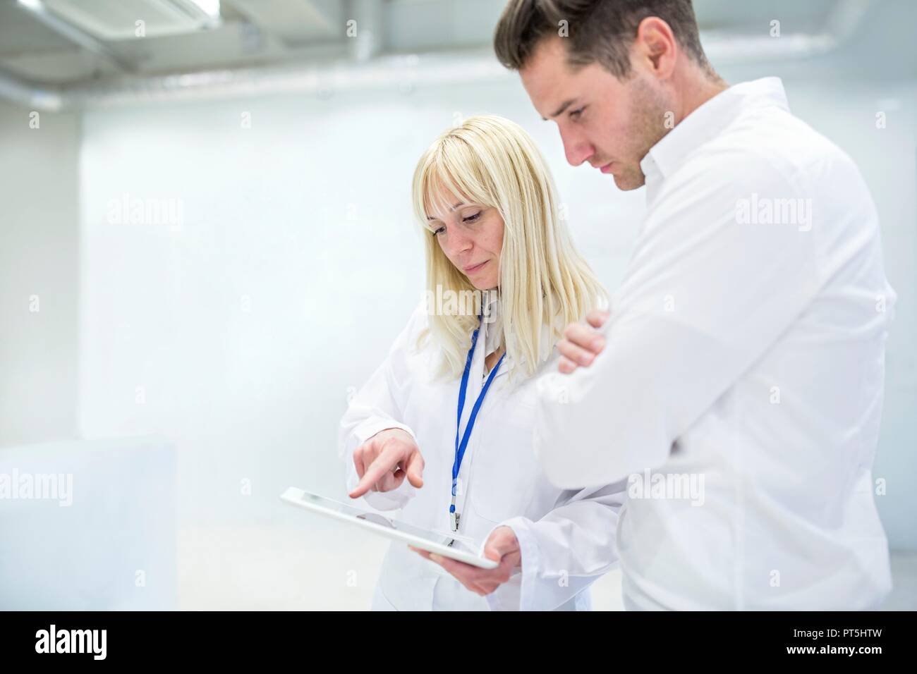 Female doctor discussing medical notes on digital tablet with consultant. Stock Photo