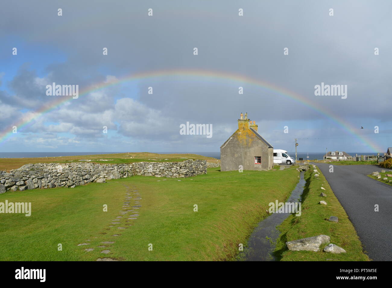 Full rainbow over the sea with fields in the foreground close to the Blackhouse Museum Arnol Isle of Lewis Outer Hebrides Western Scotland UK Stock Photo