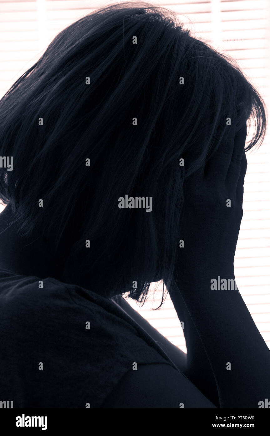 woman holding her head in despair, solitude, sadness and depression concept Stock Photo