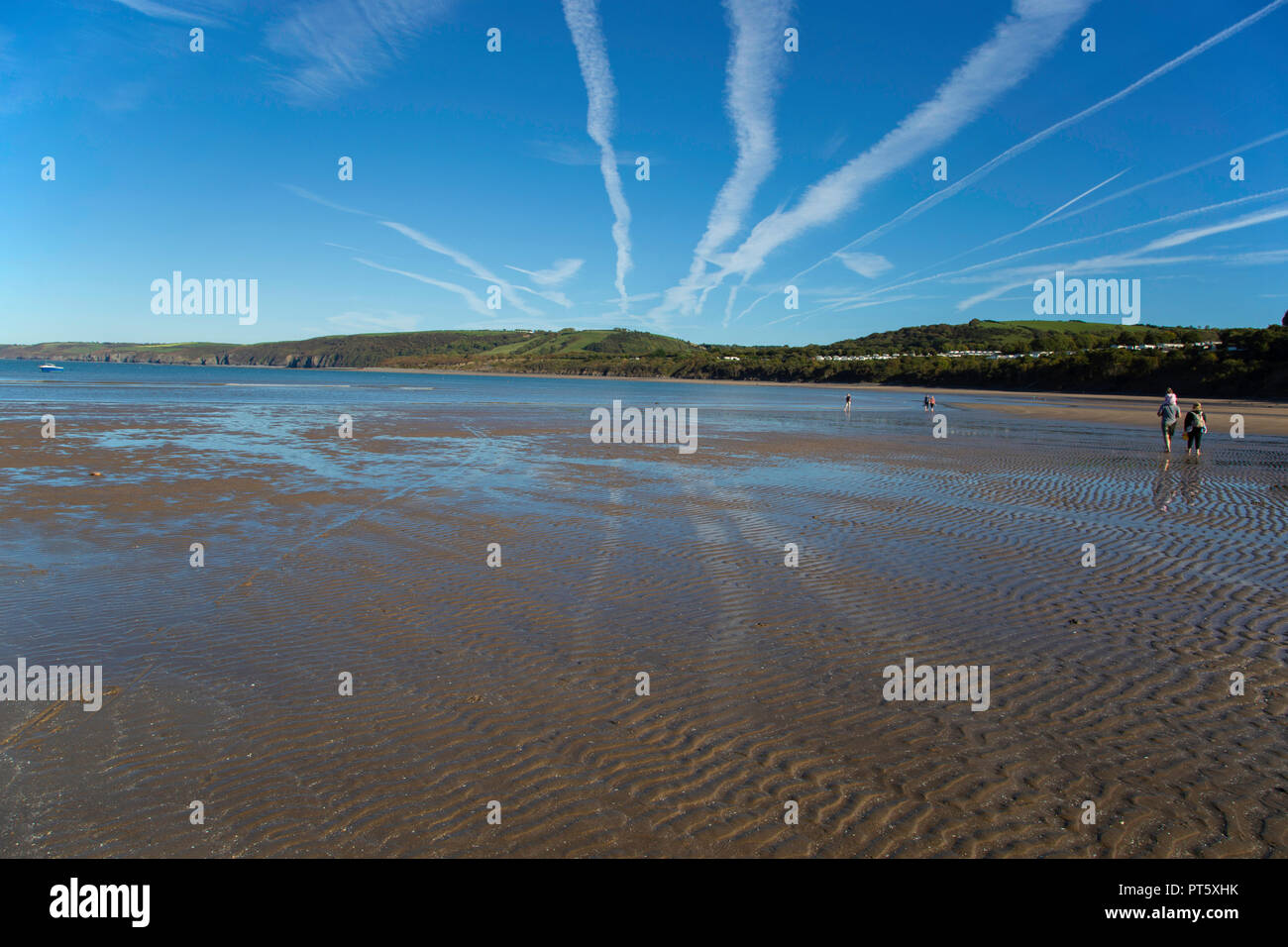 People walking on the beach in sunshine at New Quay, Ceredigion, Wales. Photograph taken 27th