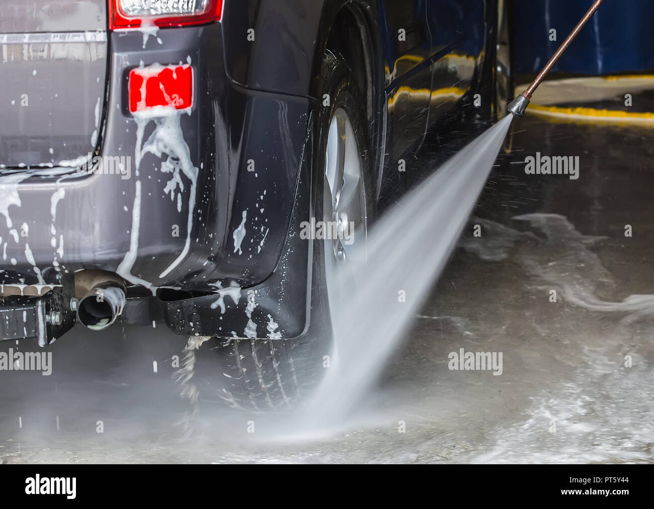 Car on a sink under a stream of water in a foam Stock Photo