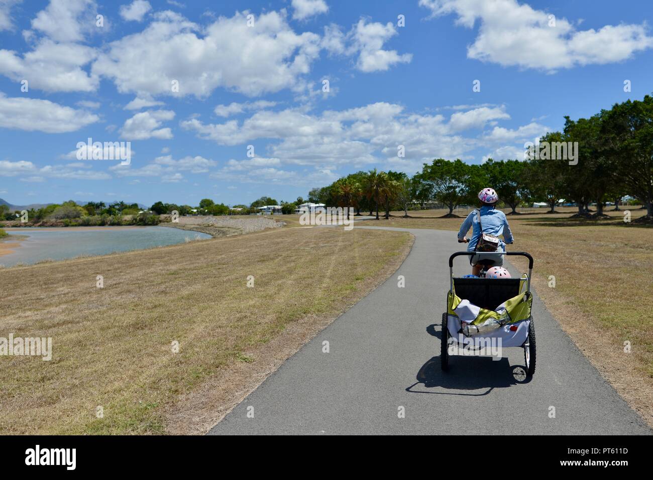 Woman riding a bicycle with a bicycle trailer for children, Townsville