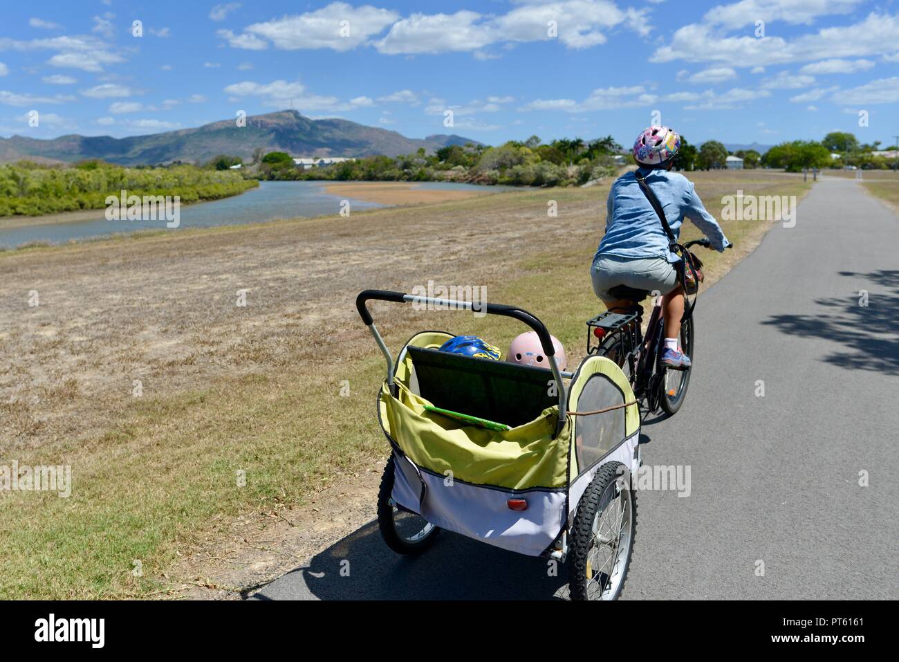 Woman riding a bicycle with a bicycle trailer for children, Townsville