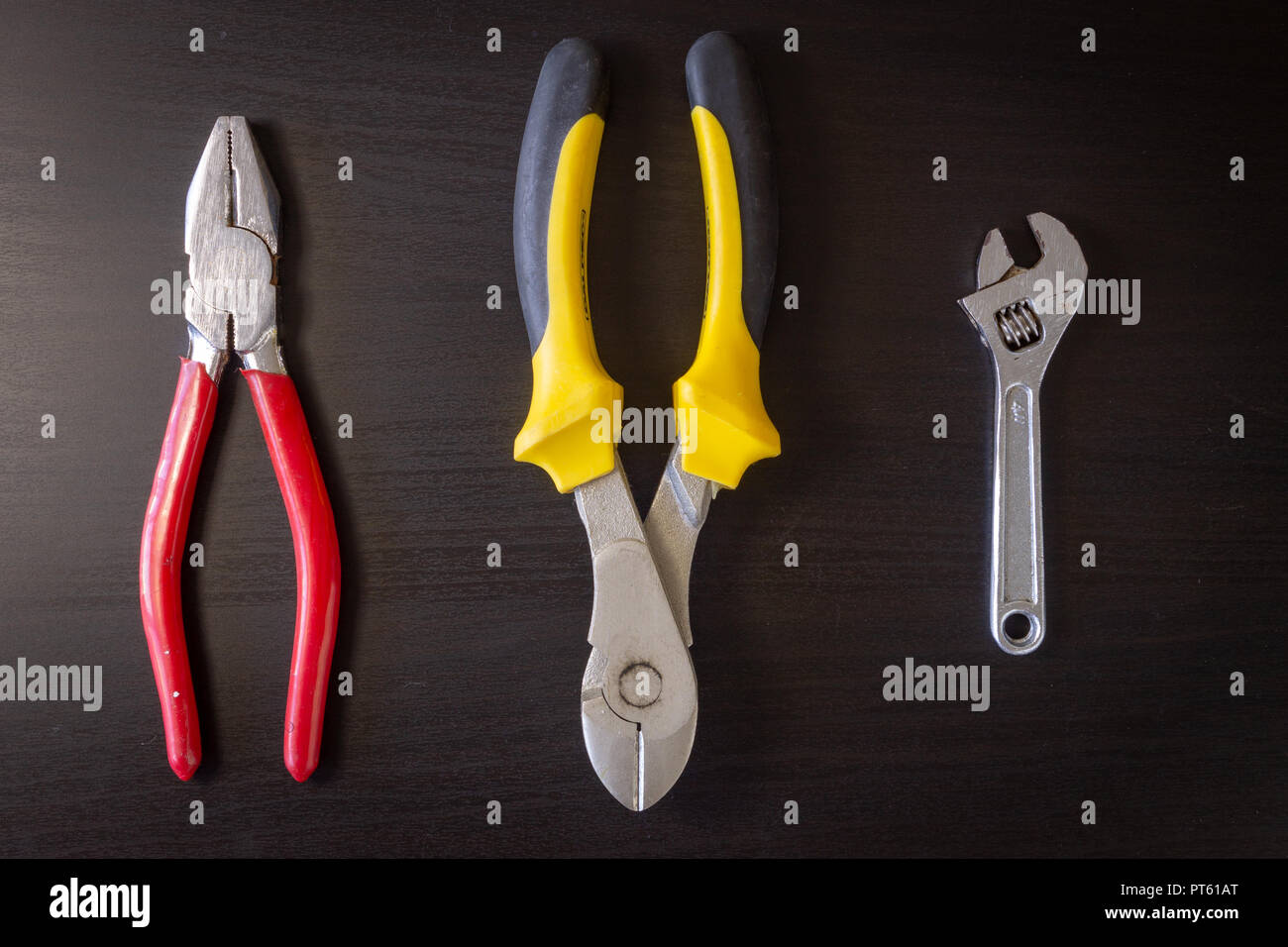 https://c8.alamy.com/comp/PT61AT/a-black-wooden-background-with-various-hardware-tools-alligned-horizontally-pliers-cutting-pliers-wrench-PT61AT.jpg