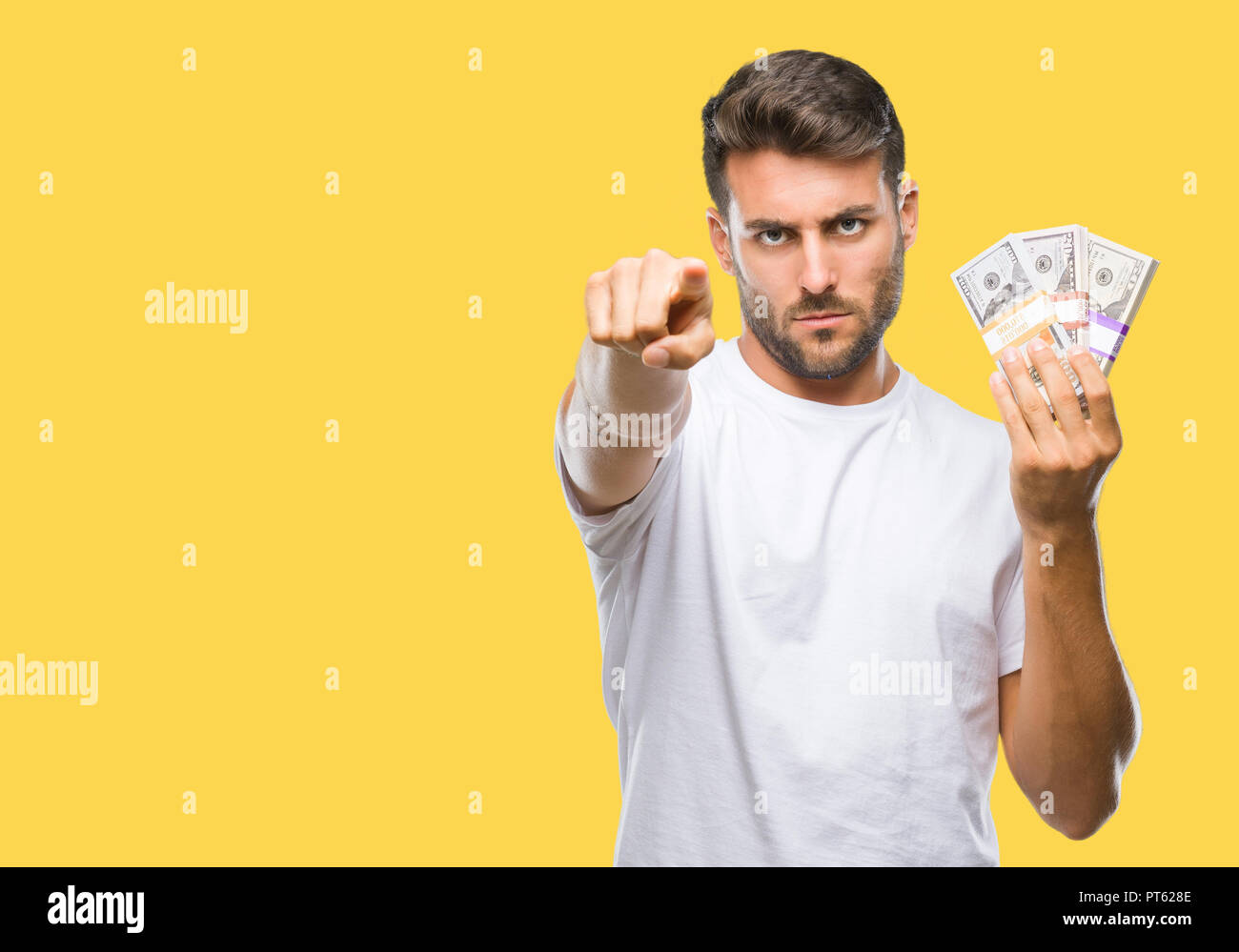 Young handsome man holding stack of dollars over isolated background ...