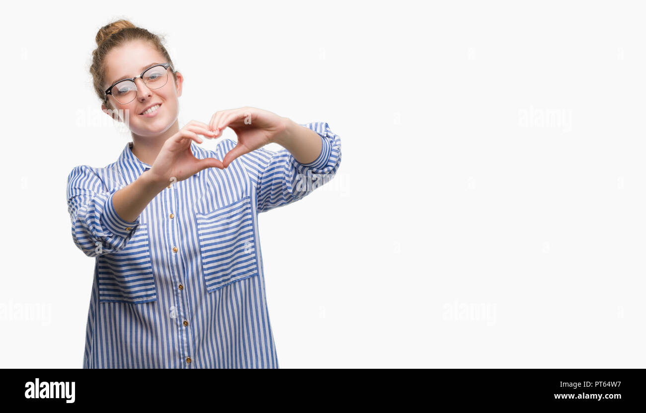 Young blonde business woman smiling in love showing heart symbol and shape with hands. Romantic concept. Stock Photo