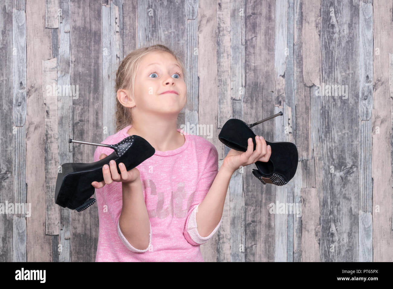 girl is holding large mother shoes with high heels and shakes them Stock Photo