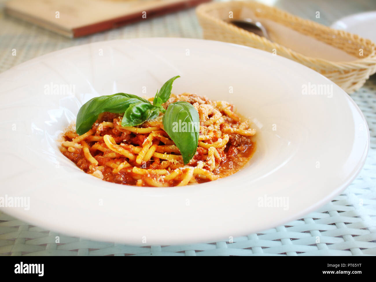 white plate with pasta bolognese with leaves of fresh basil Stock Photo