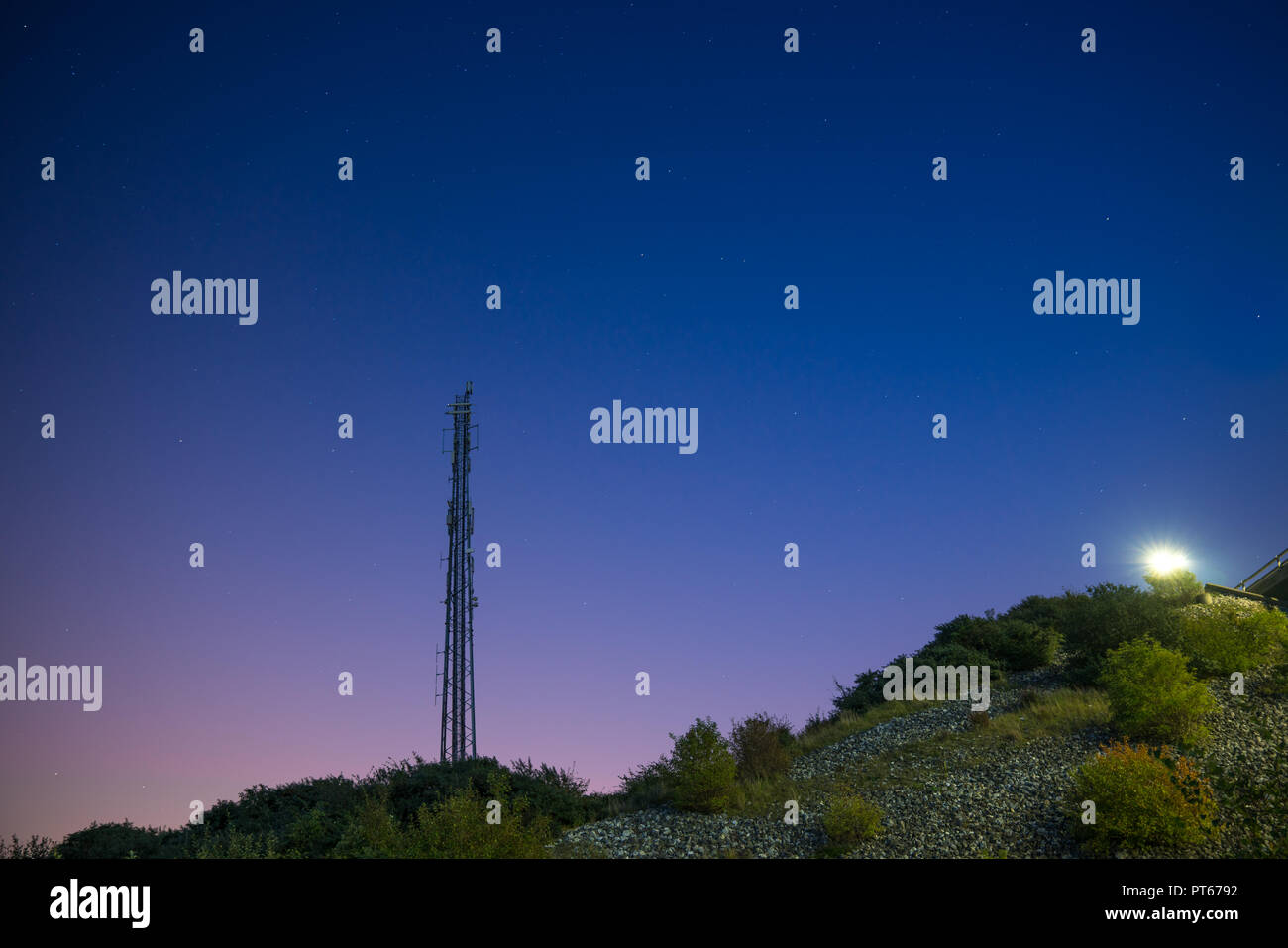 A broadcasting tower on a hill in the night with stars on the sky Stock Photo