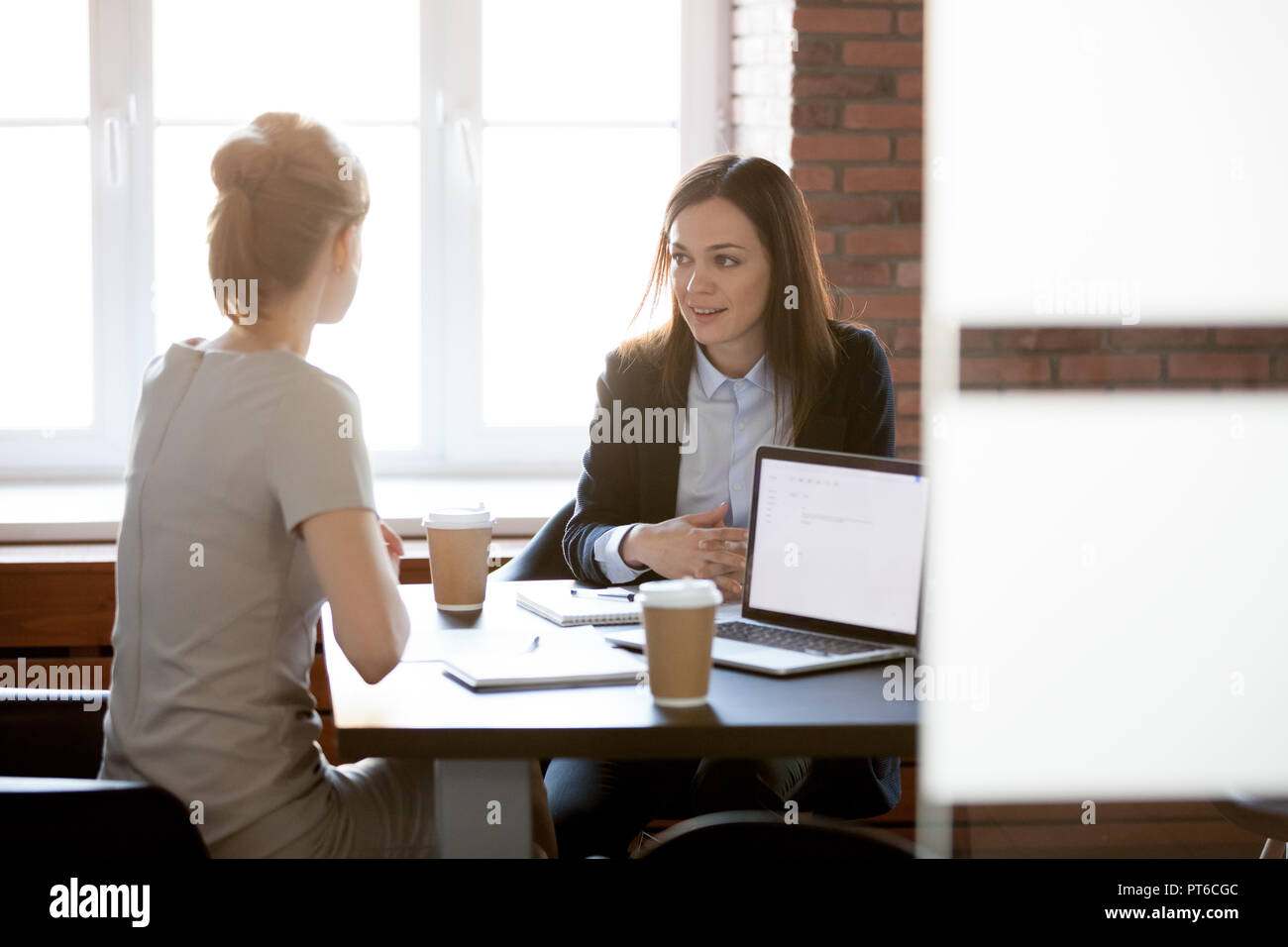 Friendly young businesswomen talking chatting in office during c Stock Photo