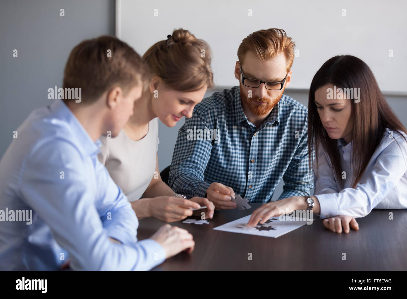 Focused team people assembling puzzle finding business solutions Stock Photo
