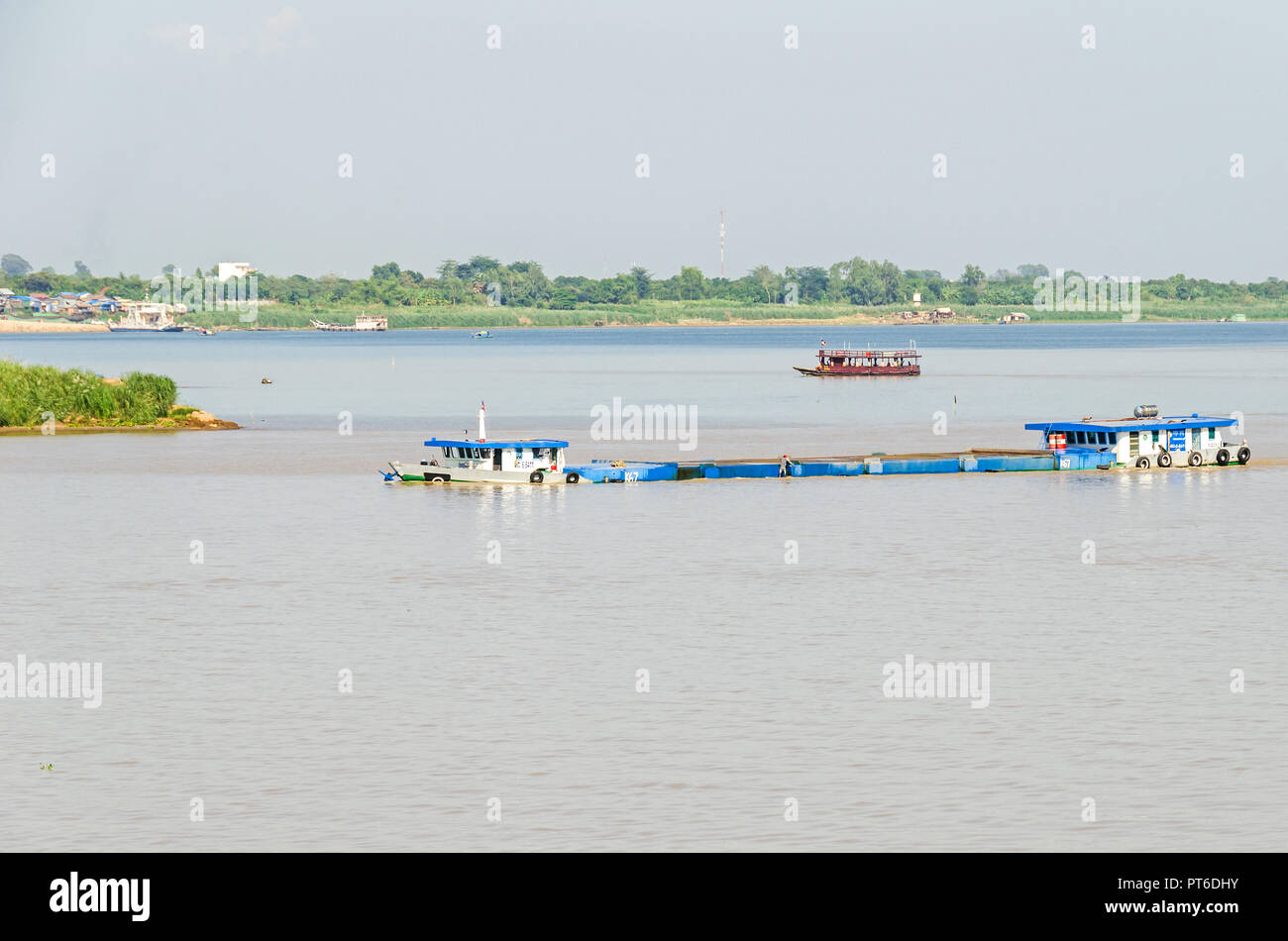 Phnom Penh, Cambodia - April 9, 2018: Cargo boat transporting gravel down the Mekong river typically very low in the water, filled up to the rim, real Stock Photo