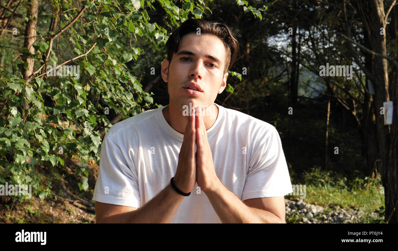 Young man praying and pleading, in nature Stock Photo
