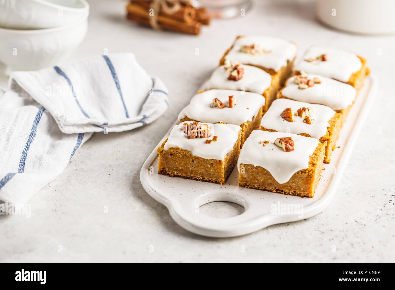 Vegan carrot cake with coconut cream and pecans on white board. Clean