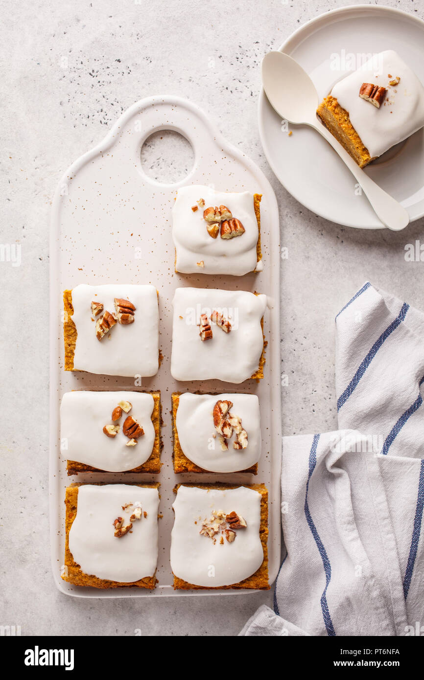 Vegan carrot cake with coconut cream and pecans on white board. Clean