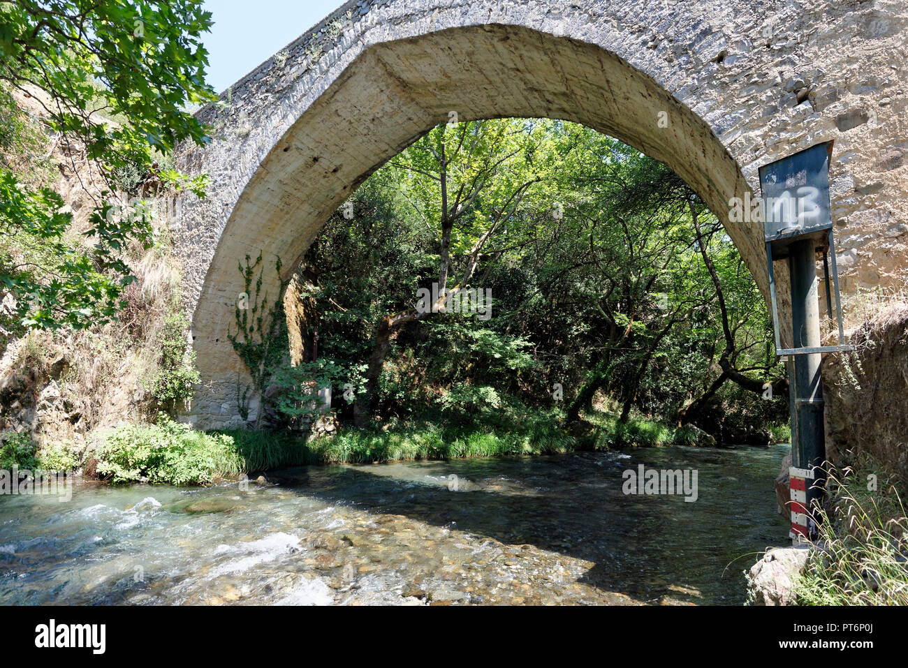 The arched stone bridge and the rushing waters of the Lousios River ...