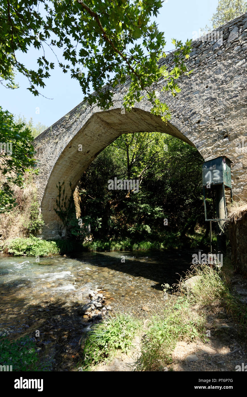 The arched stone bridge and the rushing waters of the Lousios River ...