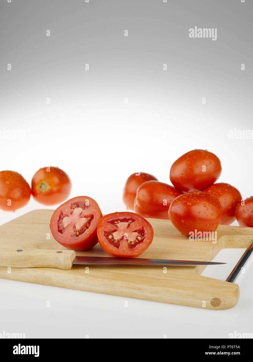 Tomatoes whole and cut on a wooden cutting board Stock Photo - Alamy