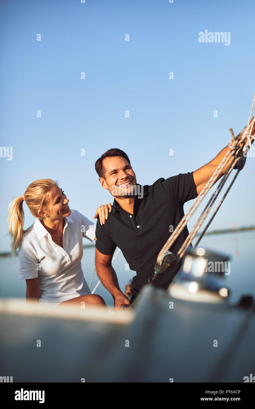 Smiling young couple sitting on the deck of their yacht enjoying an afternoon sailing together Stock Photo