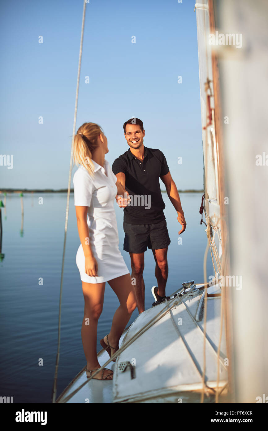 Young woman leading her smiling husband by the hand on the deck of a yacht while enjoying the day sailing together Stock Photo